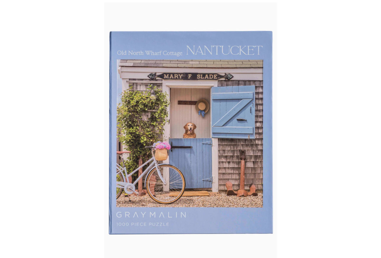 Perfect for puzzle and fine art photography enthusiasts alike, Gray Malin Nantucket 1000 Piece Book Box Puzzle features "Old North Wharf Cottage, Nantucket" from Gray’s best-selling collection, 1000 pieces