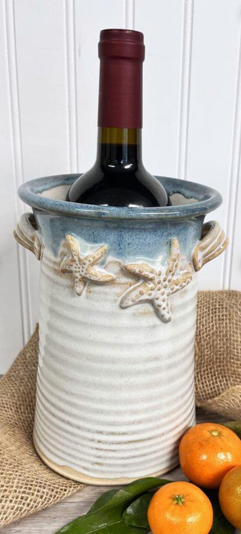 Starfish crock in blue rim with warm tan and creams for bottom with wine bottle 