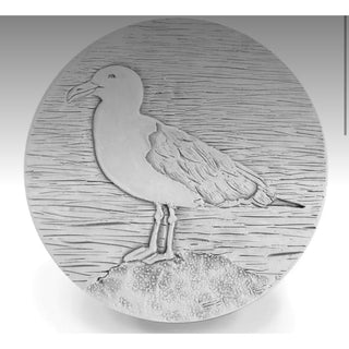 Showing seagull coaster on rock with waves etched in background 