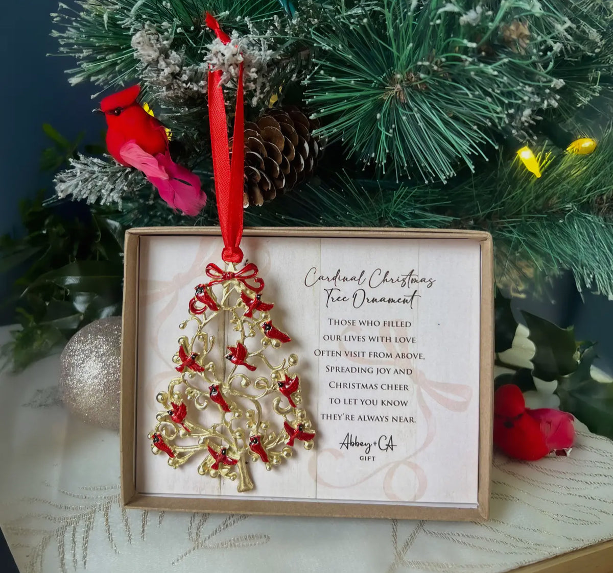 This beautiful  ornament adds a meaningful, memorial sentiment to your tree.  Cast metal, gold plated with vibrant translucent red and black cardinals and hangs in a red satin ribbon. 
Comes gift boxed

2 3/4 w x 4” h