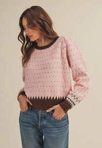 The warm pink and brown hies in this weather are perfect for getting cozy this winter. It also makes a great transition piece. The round neckline in contrasting colors adds to the details of this sweater.  