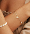 Silver shell charm bracelet shown on wrist 
