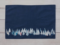 Dark blue side shown.  These 100% cotton placemats are reversible. The front side has sailboats all over and the reverse is a dark blue with a line of sailboats. 
