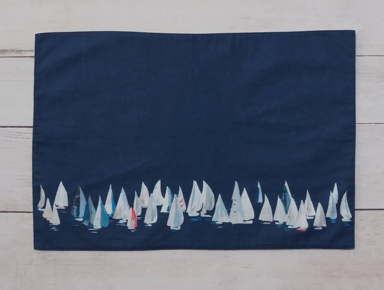 Dark blue side shown.  These 100% cotton placemats are reversible. The front side has sailboats all over and the reverse is a dark blue with a line of sailboats. 