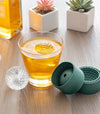 Score big at any sports party event! This set of 2 ice molds makes 2 large ice balls (dia. 2" / 5cm). Hand wash only.  Showing the golf ball ice cube in a drink 