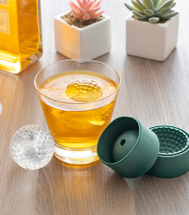Score big at any sports party event! This set of 2 ice molds makes 2 large ice balls (dia. 2" / 5cm). Hand wash only.  Showing the golf ball ice cube in a drink 