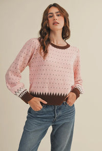 The warm pink and brown hies in this weather are perfect for getting cozy this winter. It also makes a great transition piece. The round neckline in contrasting colors adds to the details of this sweater.  