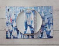 These 100% cotton placemats are reversible. The front side has sailboats all over and the reverse is a dark blue with a line of sailboats. 
Shown with plate and matching napkins 