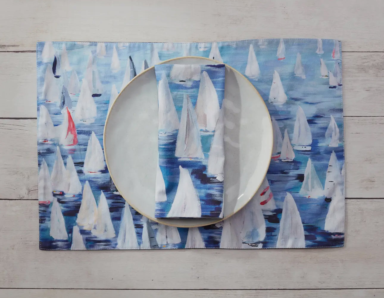 These 100% cotton placemats are reversible. The front side has sailboats all over and the reverse is a dark blue with a line of sailboats. 
Shown with plate and matching napkins 