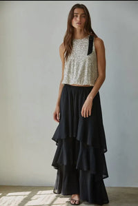This sleeveless crop top combines woven polyester spandex fabric with a shimmering sequin finish for a blend of comfort and style. Featuring a round neckline and a delicate bow trim, it offers a polished look, while the elasticband hem ensures a secure fit. The back keyhole detail adds subtle elegance, and the rayon spandex lining provides smooth wearability. Ideal for occasions that call for a sophisticated yet playful 