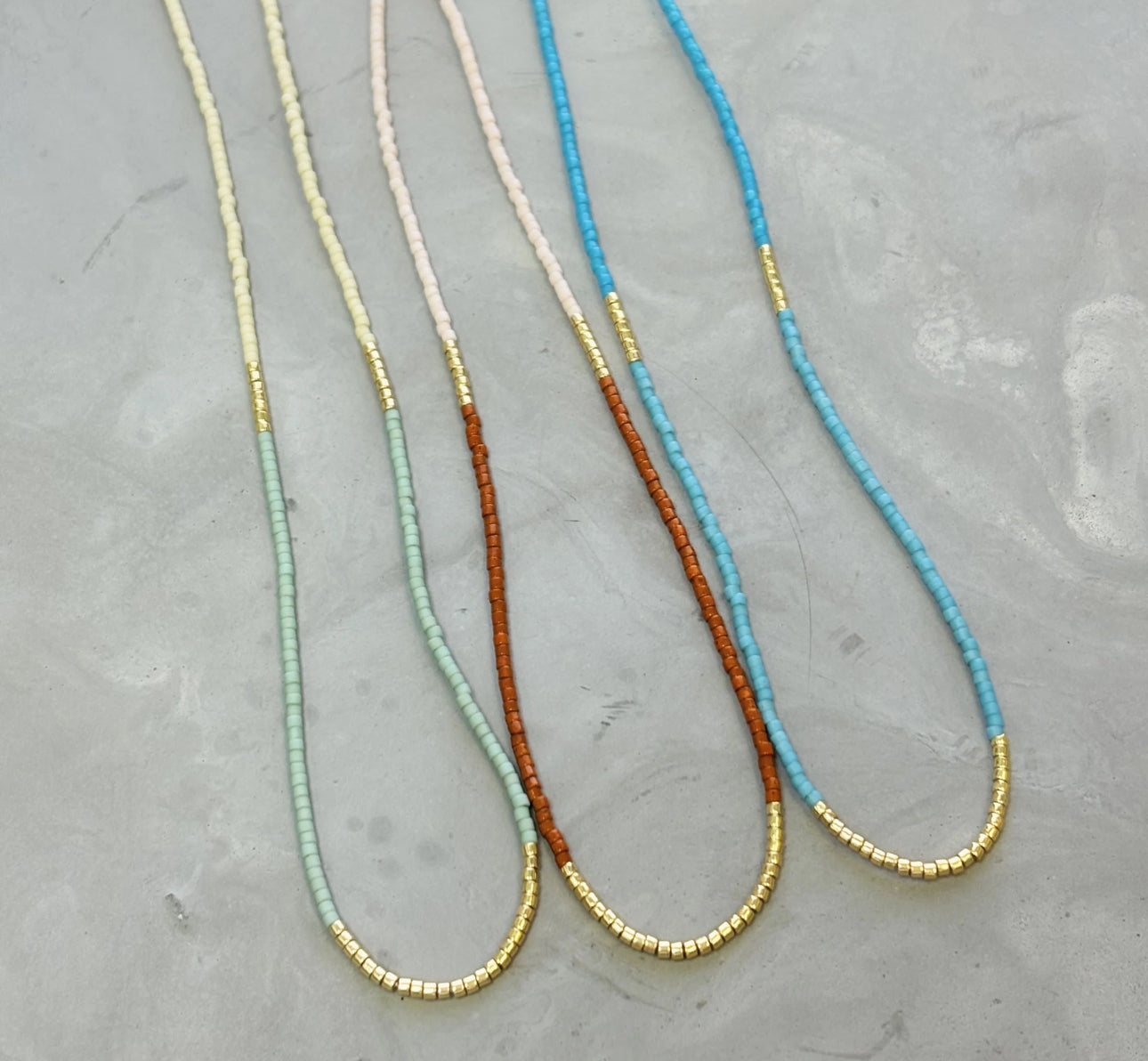 Our  necklace is handcrafted with a touch of gold in a minimalist style.   

•Seed beads in your choice of color combination 
•Hand strung in a modern pattern
•14kt Gold-Filled beads & spring clasp

•16 or 18 inch in length with an optional 2 inch extender 