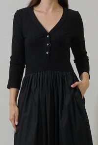 Make an effortless statement in this ultra flattering, versatile dress. It features a rib knit bodice and flared, gathered skirt for a beautifully balanced silhouette, finished with long sleeves, a split neckline, and button detail. A dropped waist and functional pockets add comfort and ease. Style with boots and a crossbody or dress it up with heels and bold accessories.

- Midi
- Long sleeves
- Knit
- Pockets
- Color: Black

Size + Fit
- Model is 5'9" and wearing size XS
- Measurements taken from size S
-