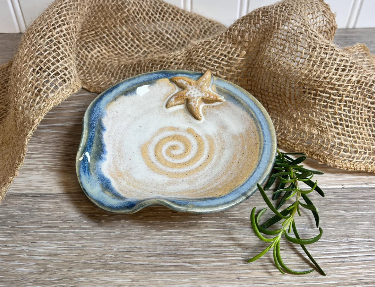 Elevate your cooking experience with our beautifully handcrafted ceramic spoon rest! Perfect for keeping your countertops clean and organized. Adorned with a starfish painted in warm blues and sand hues, this spoon rest is a great addition to your coastal home. 